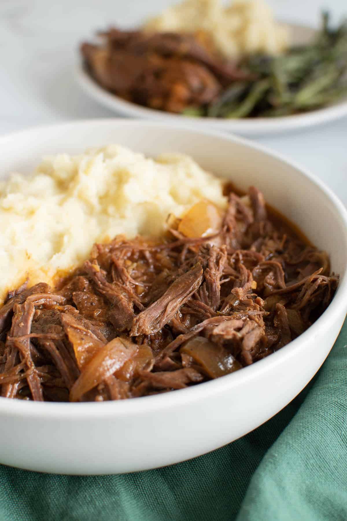 Close up of shredded beef and mashed potatoes.