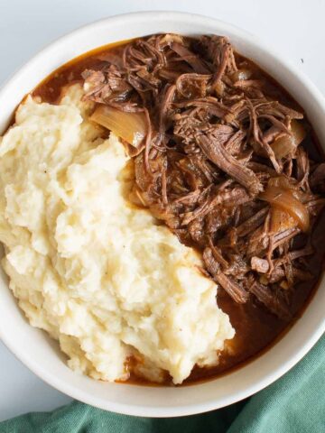 A bowl of shredded braising steak and mashed potatoes.