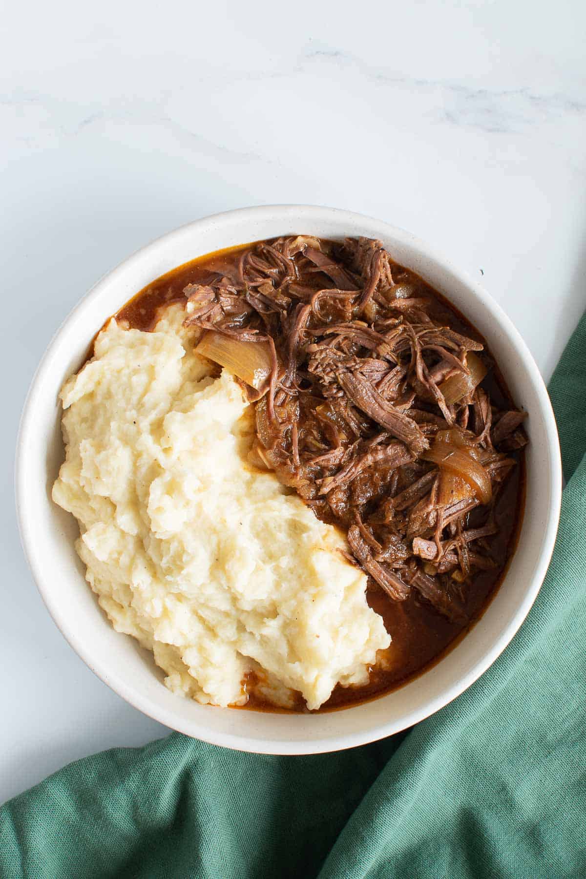 Slow cooker braising steak and onions, with mashed potatoes on the side.