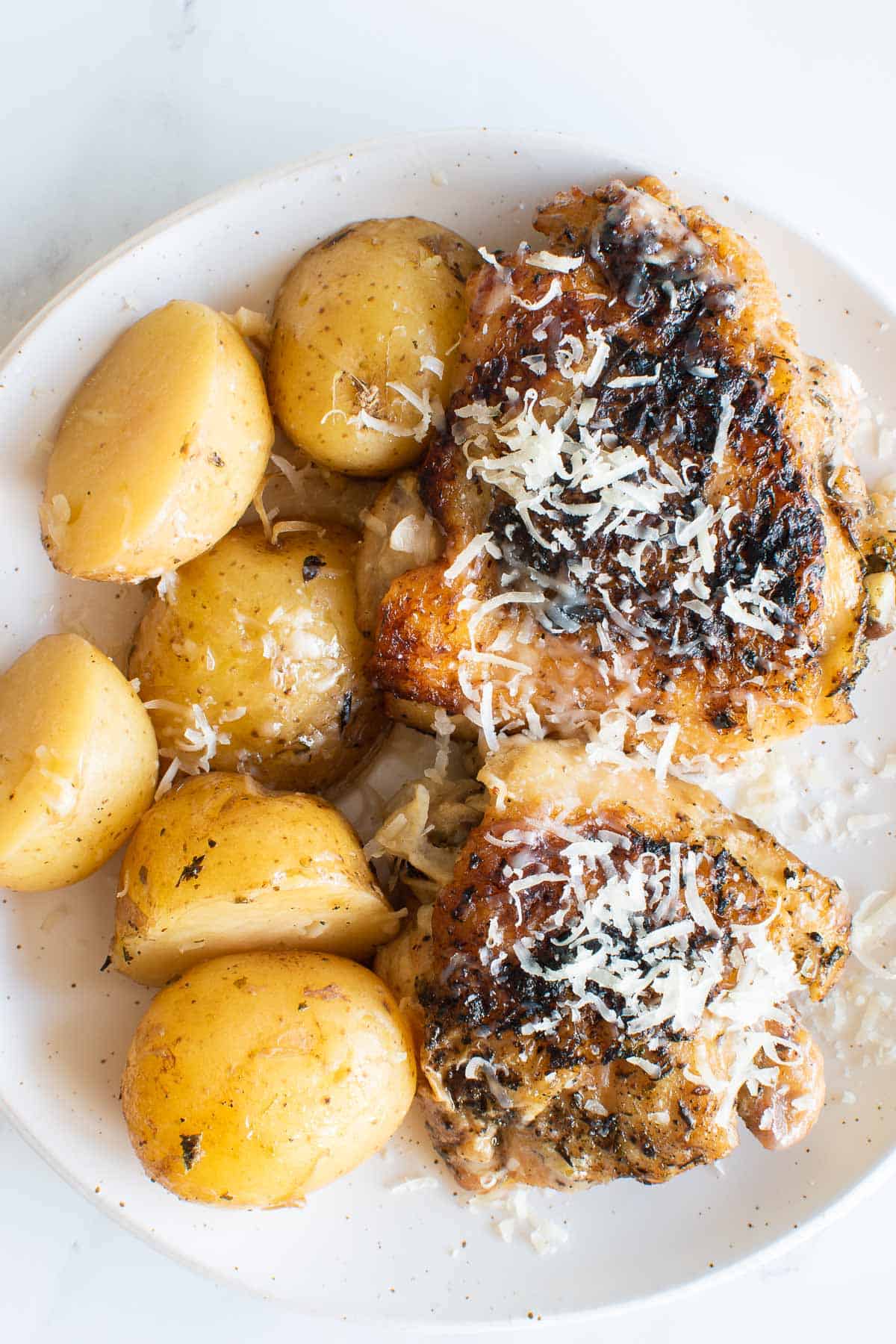 A plate of garlic Parmesan chicken and potatoes.