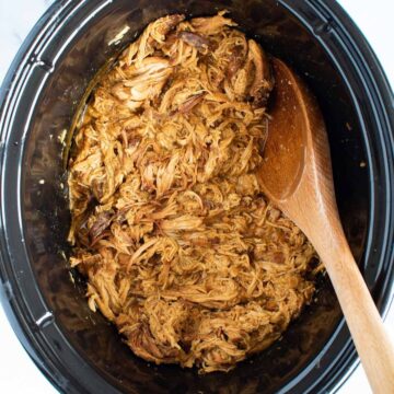 Shredded honey mustard chicken in a slow cooker.