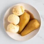 Brandied pears and ice cream on a plate.