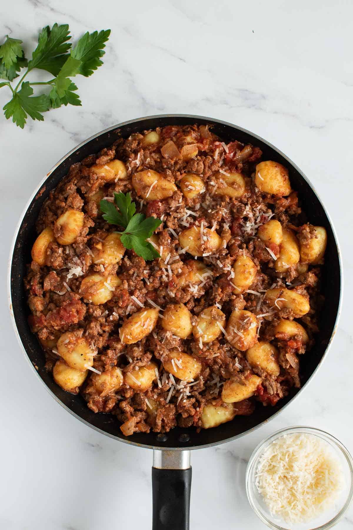 A frying pan with gnocchi in bolognese sauce.