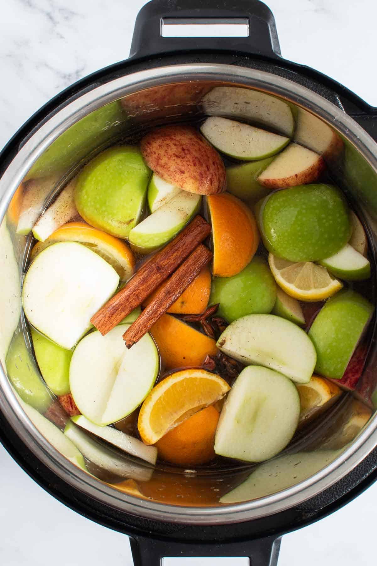 Apples, oranges and cinnamon sticks in Instant Pot.