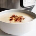 Instant Pot cauliflower soup topped with bacon in a bowl.