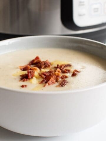Instant Pot cauliflower soup topped with bacon in a bowl.