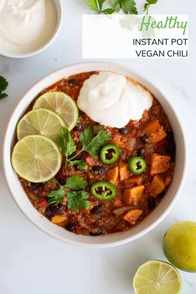 A bowl of vegan chili with sour cream and lime on top.