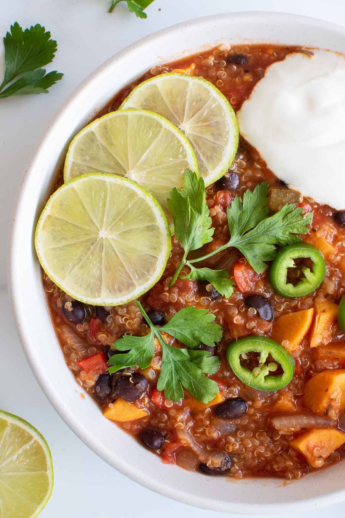 Quinoa and sweet potato vegan chili topped with lime and sour cream.