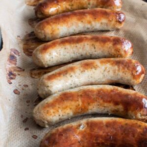 Baked bratwurst on a baking sheet.