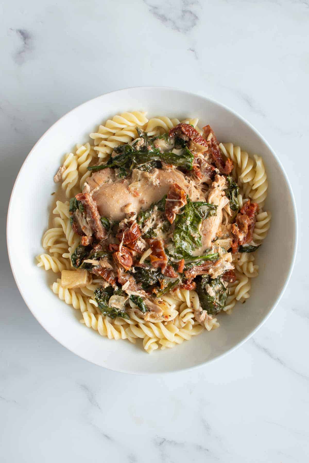 Slow cooked chicken with cream, spinach and sun dried tomatoes over pasta.