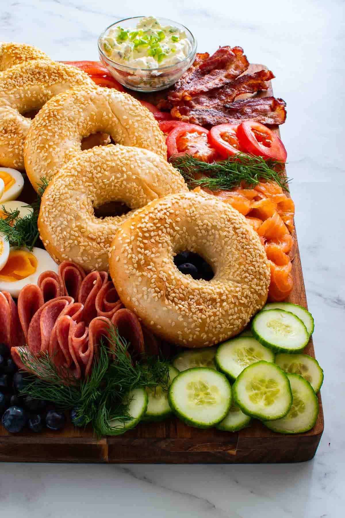 A charcuterie board with bagels and toppings.