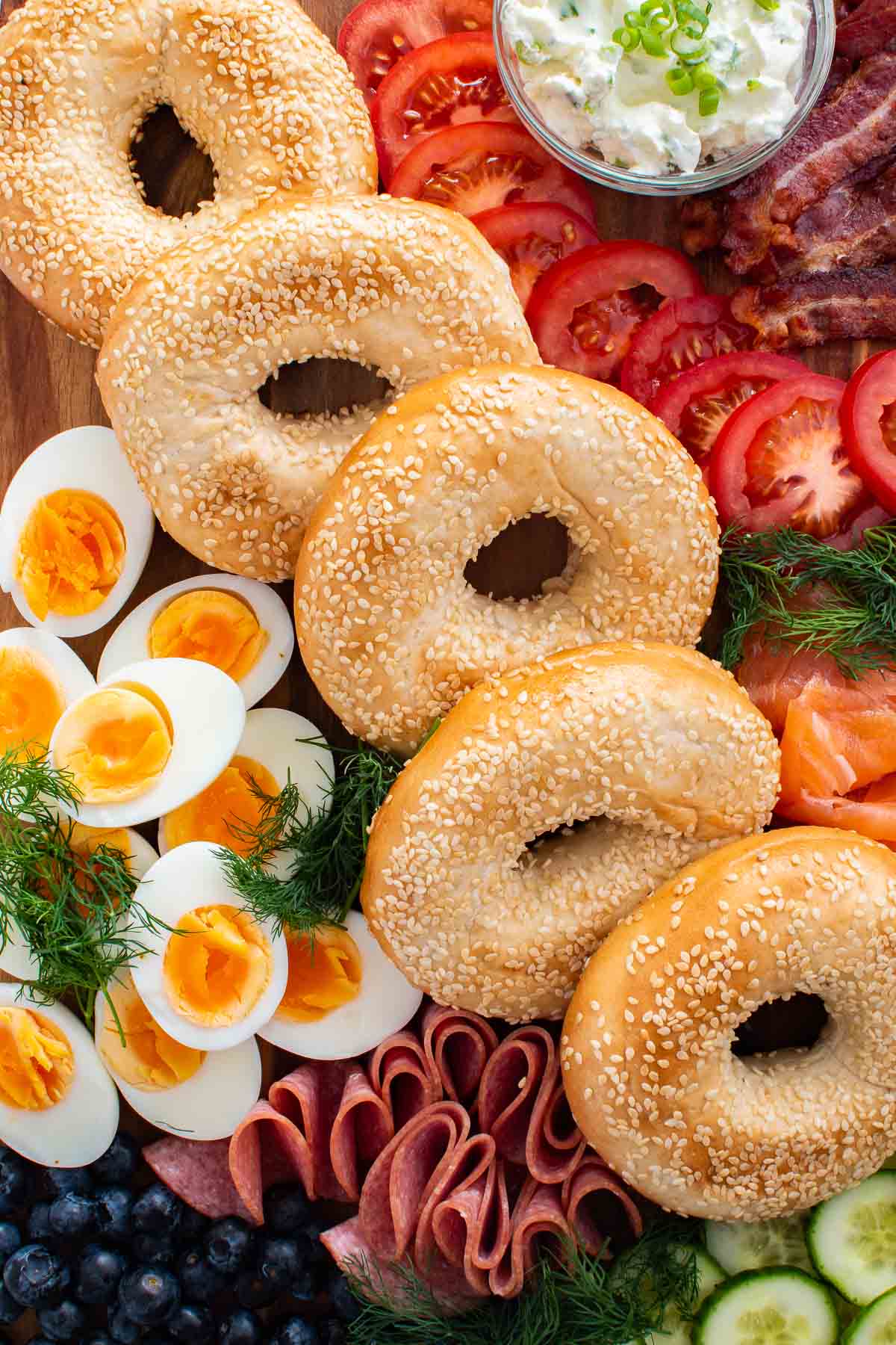 Breakfast charcuterie board with bagels, eggs, bacon and toppings.