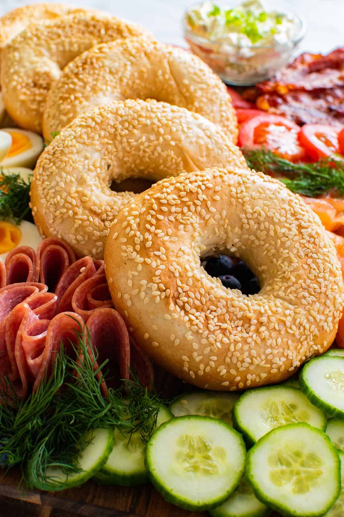 Bagel breakfast board idea with salami, cucumbers and other toppings.