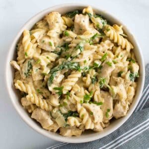 Chicken pasta with spinach and alfredo sauce in a bowl.