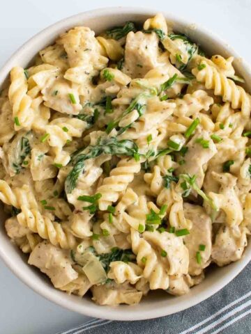 Chicken pasta with spinach and alfredo sauce in a bowl.