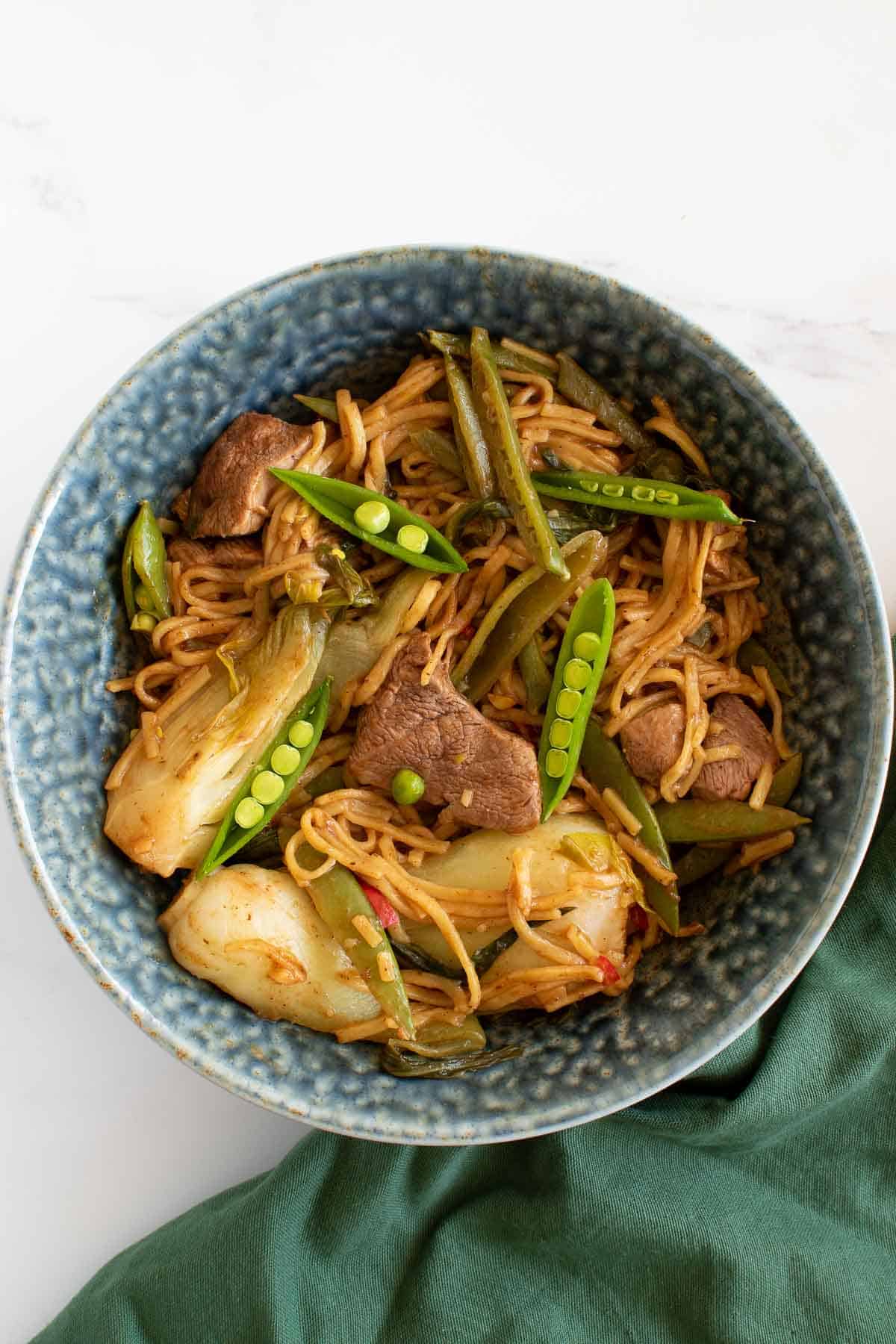 A large bowl of Duck stir fry with noodles.