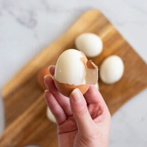 A hand peeling a hard boiled egg.