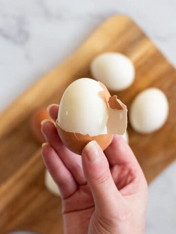 A hand peeling a hard boiled egg.