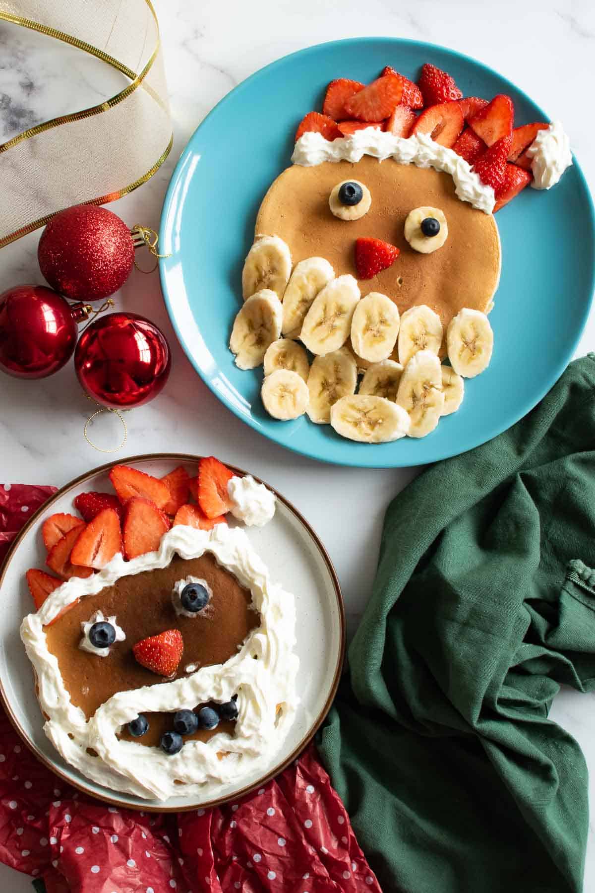 Two plates with santa pancakes on a Christmas table.