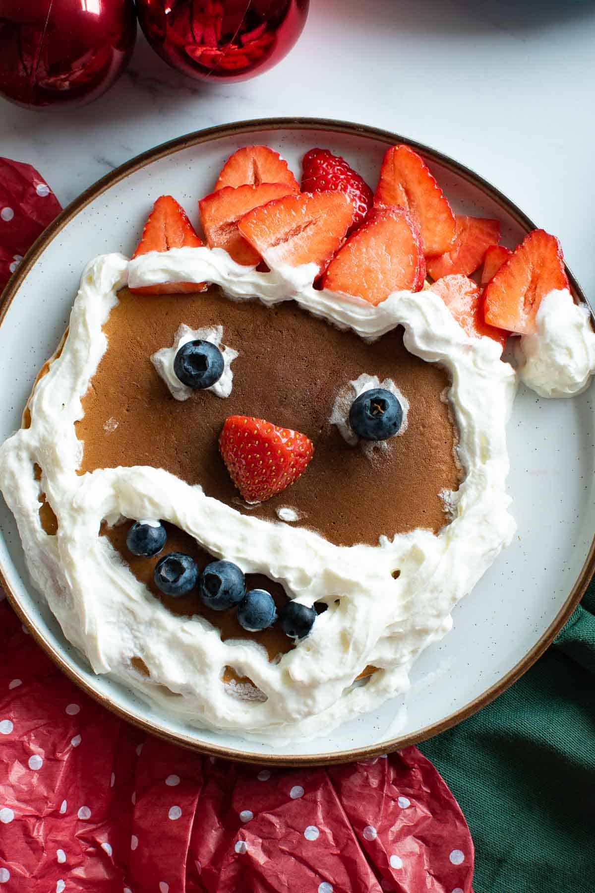 Santa pancake with strawberries, blueberries and whipped cream.