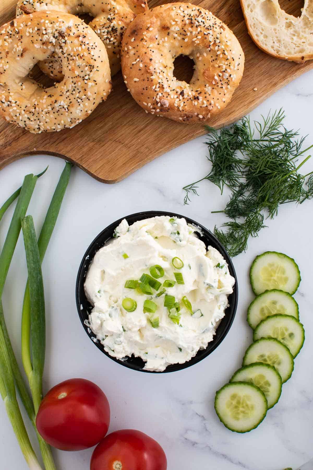 Scallion cream cheese bagel spread, with bagels and vegetables on the side,
