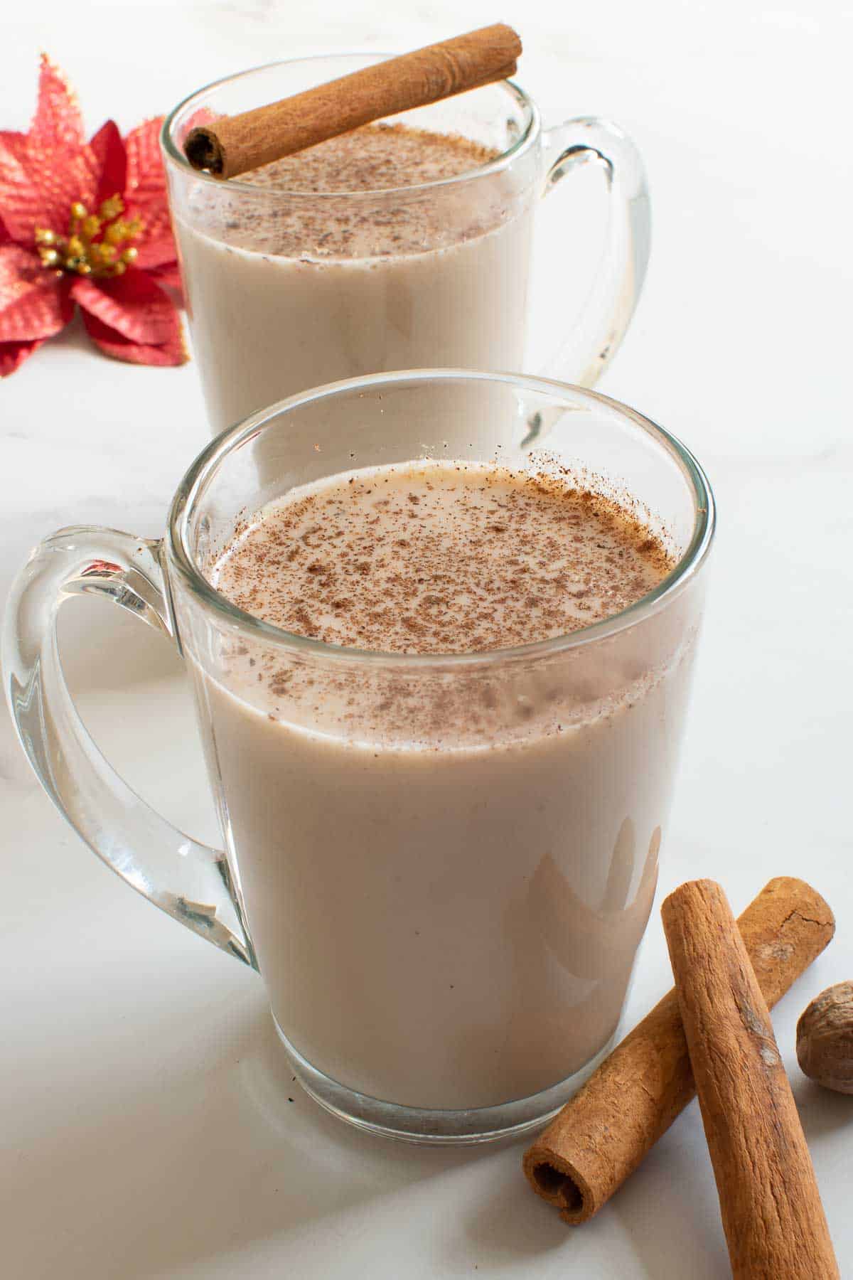 Cups of eggnog with nutmeg on top.