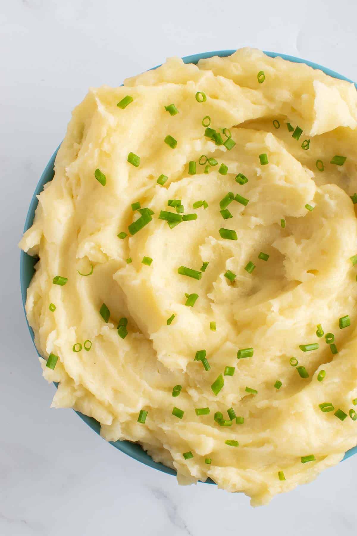 A bowl with whipped potatoes and chives.