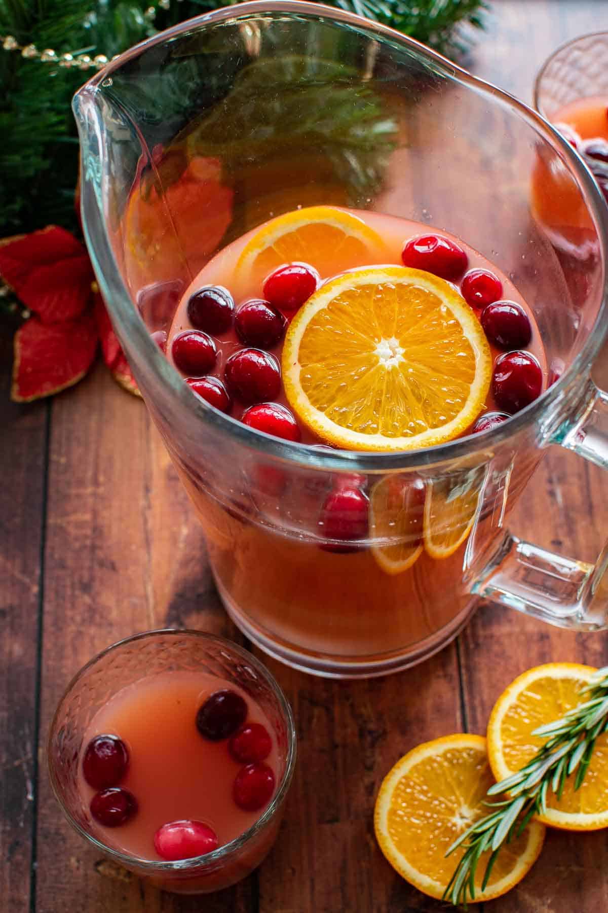 A pitcher of christmas punch on a table.