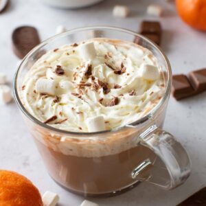 Orange hot chocolate topped with marshmallows and whipped cream.