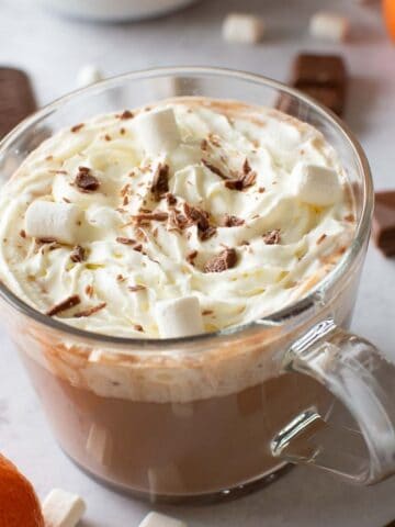 Orange hot chocolate topped with marshmallows and whipped cream.