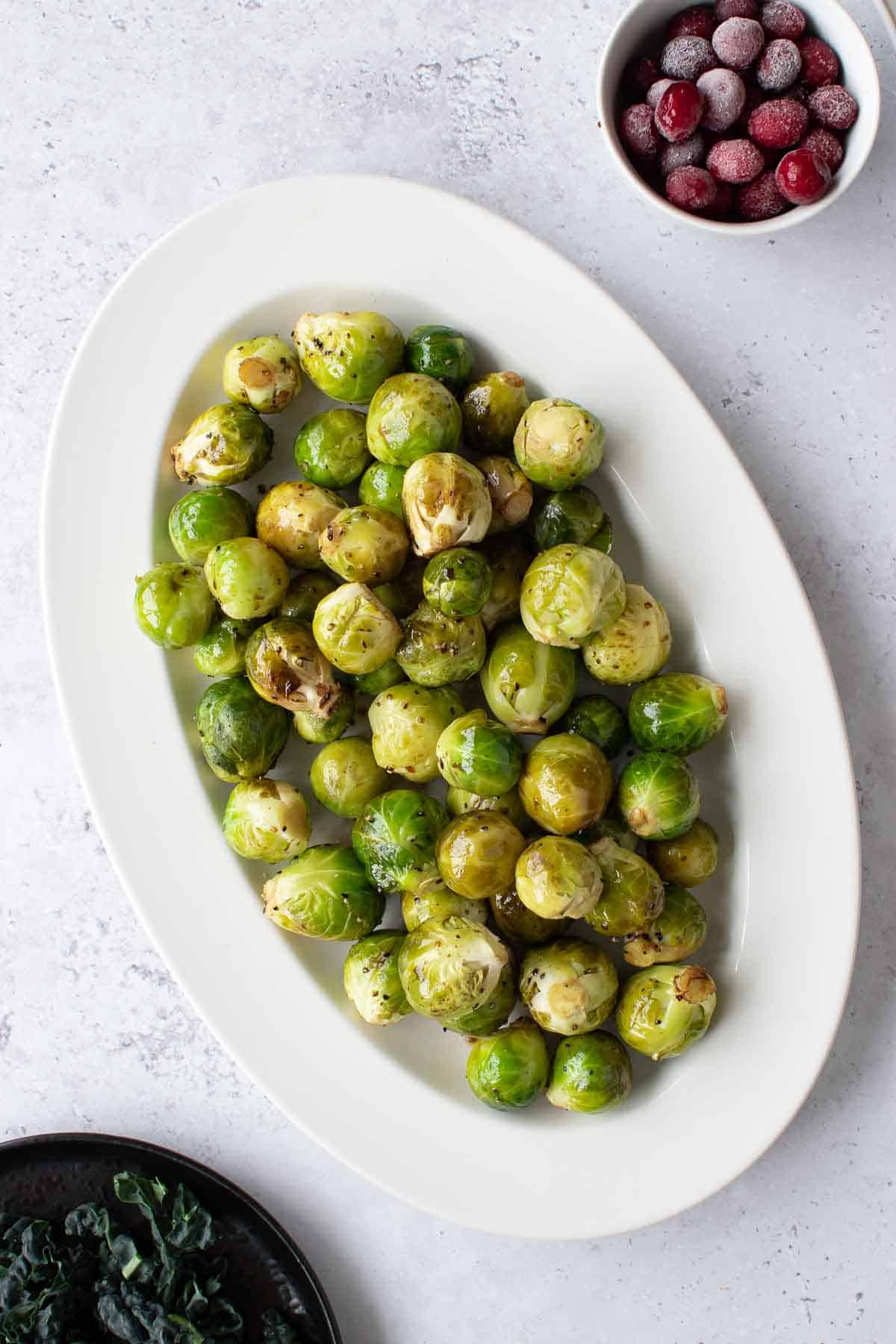 Slow cooker brussels sprouts on a plate, surrounded by festive side dishes.