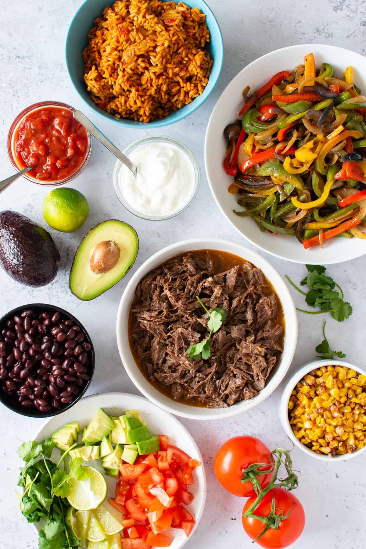 Shredded beef on a table with tex mex side dishes.