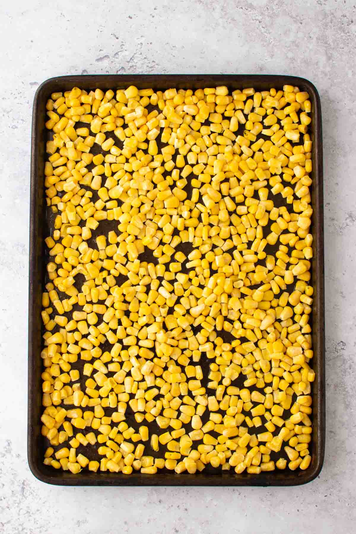 Frozen corn on a baking sheet.