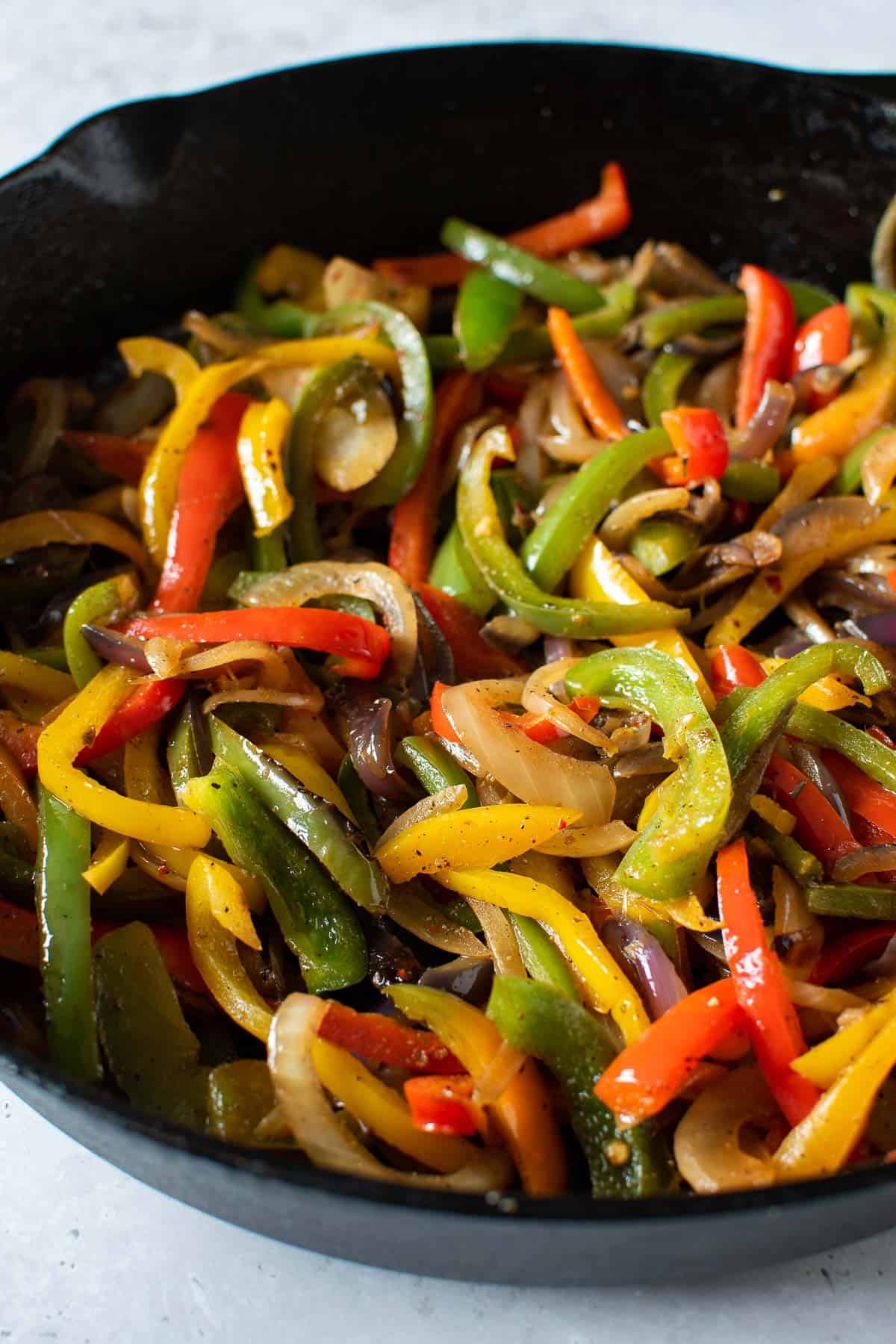 A cast iron pan with sliced peppers and onions.