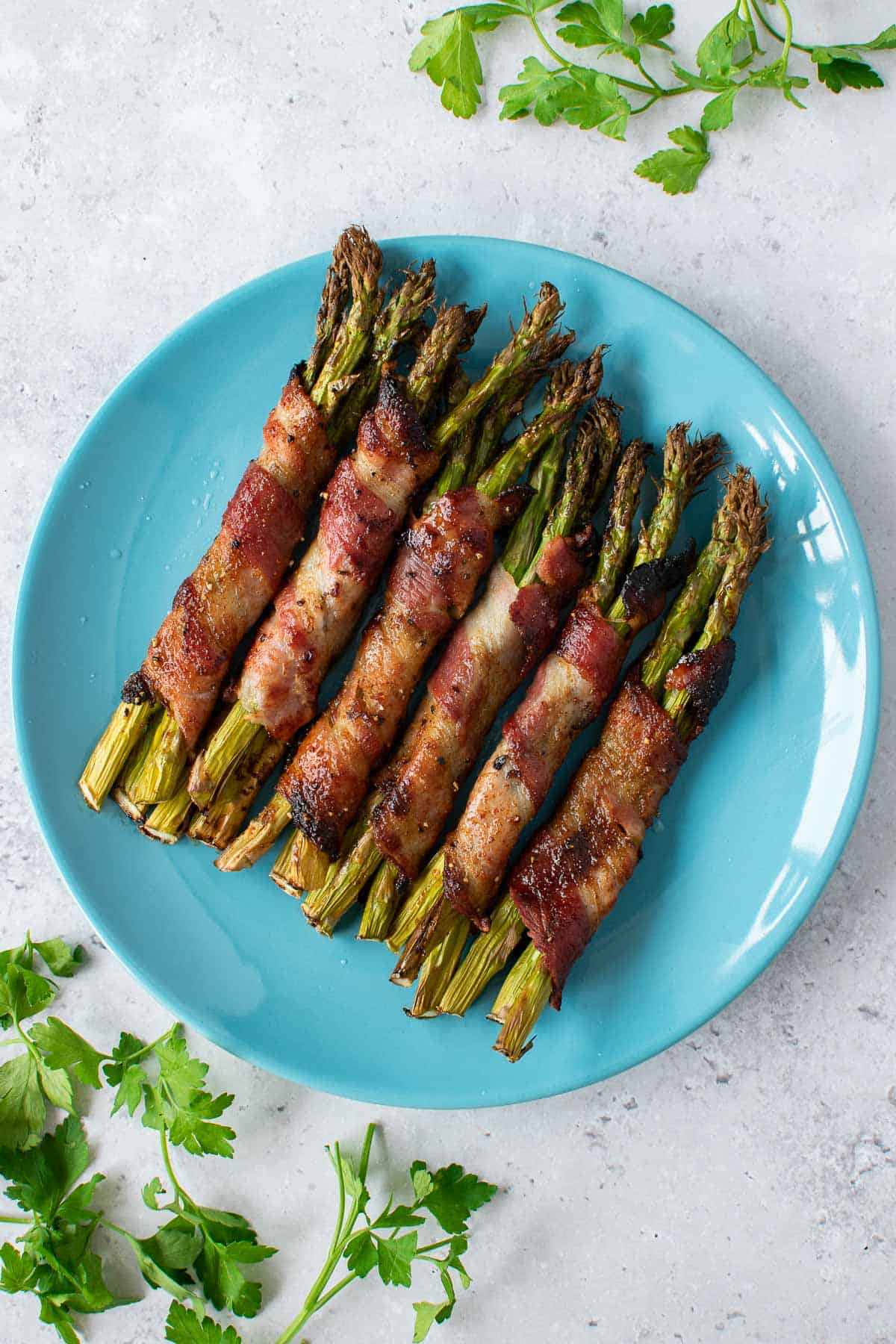 Bundles of asparagus wrapped in bacon, marinated with maple syrup and seasoning.