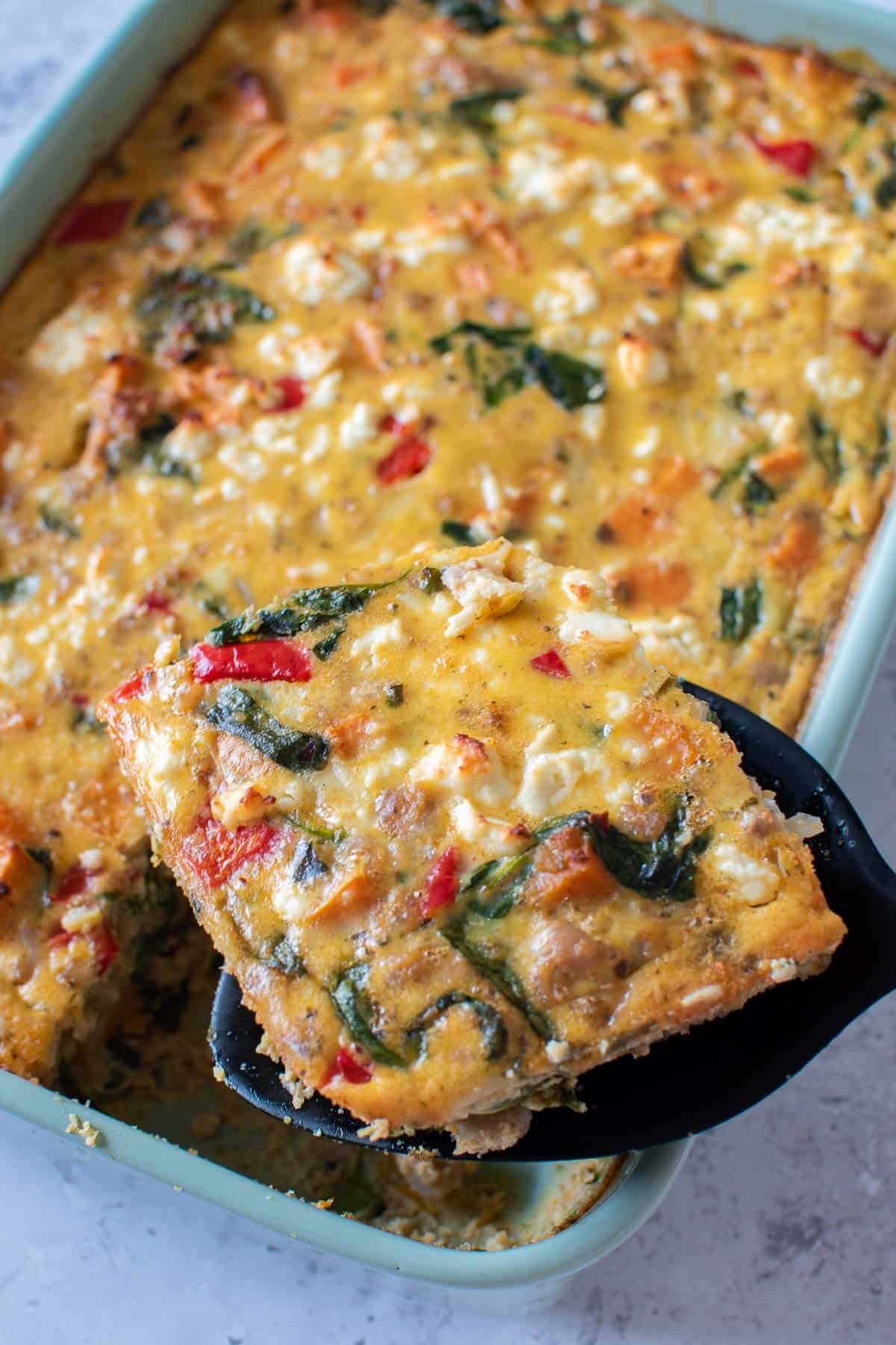 Sweet potato sausage breakfast casserole, with a spatula serving up a slice.