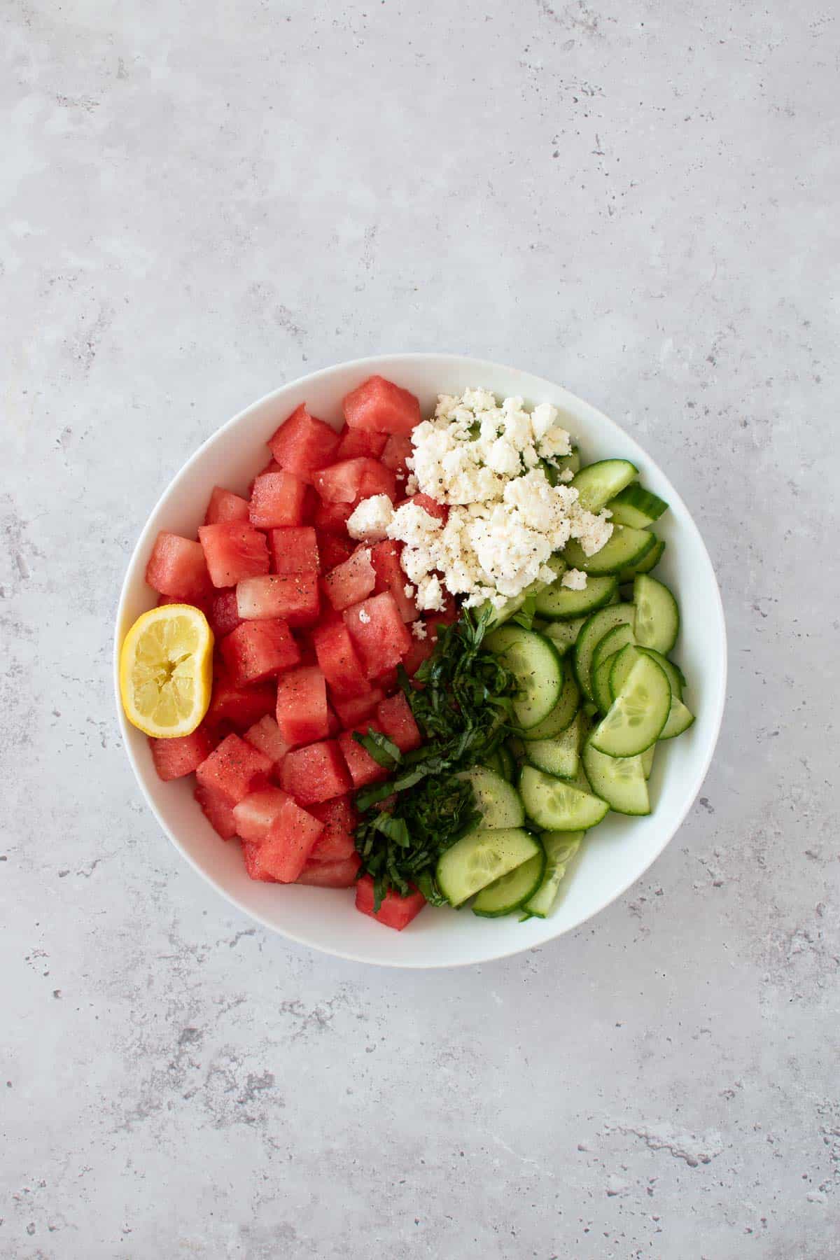 The watermelon salad ingredients added to a bowl.