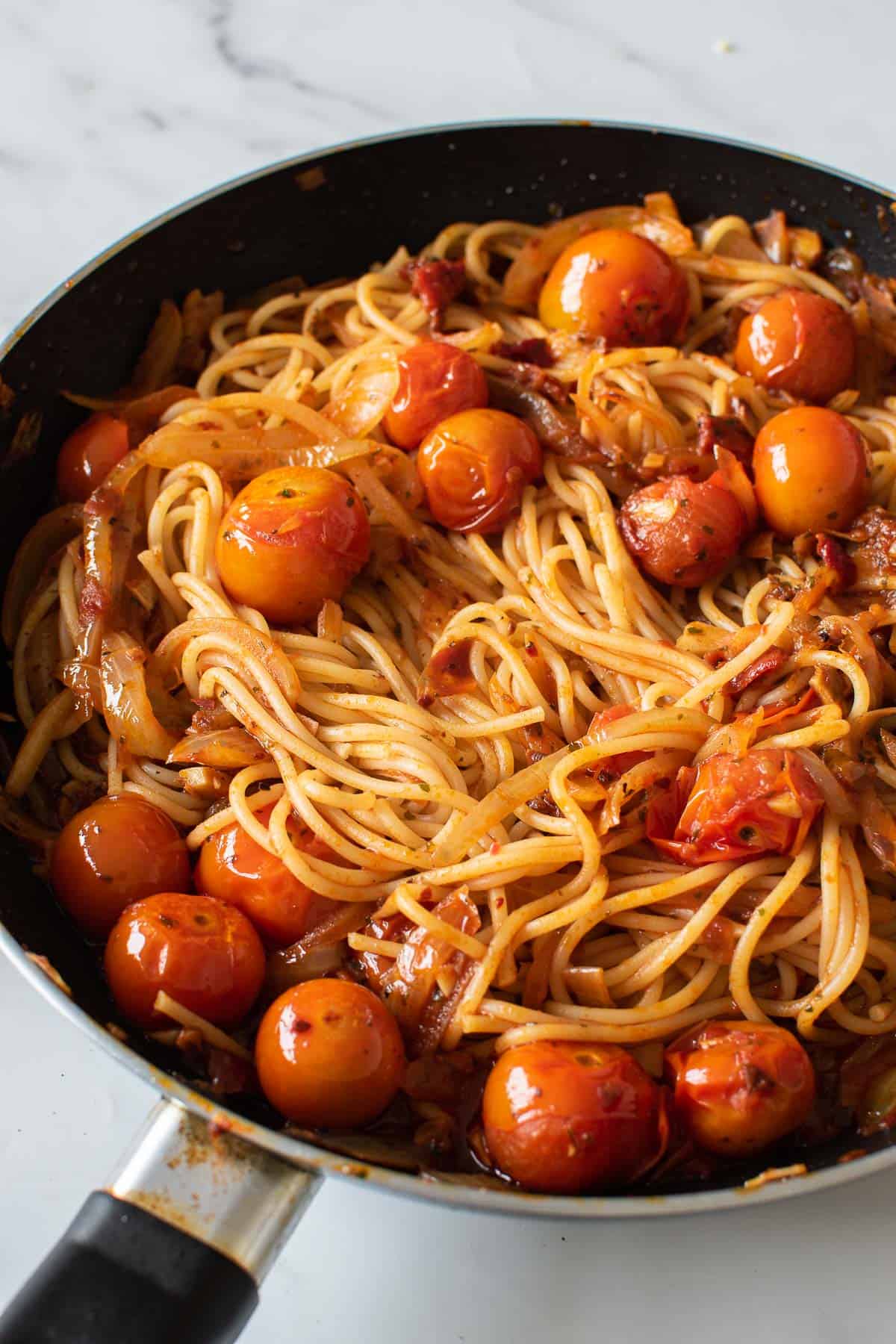 Harissa and tomato spaghetti in a frying pan.