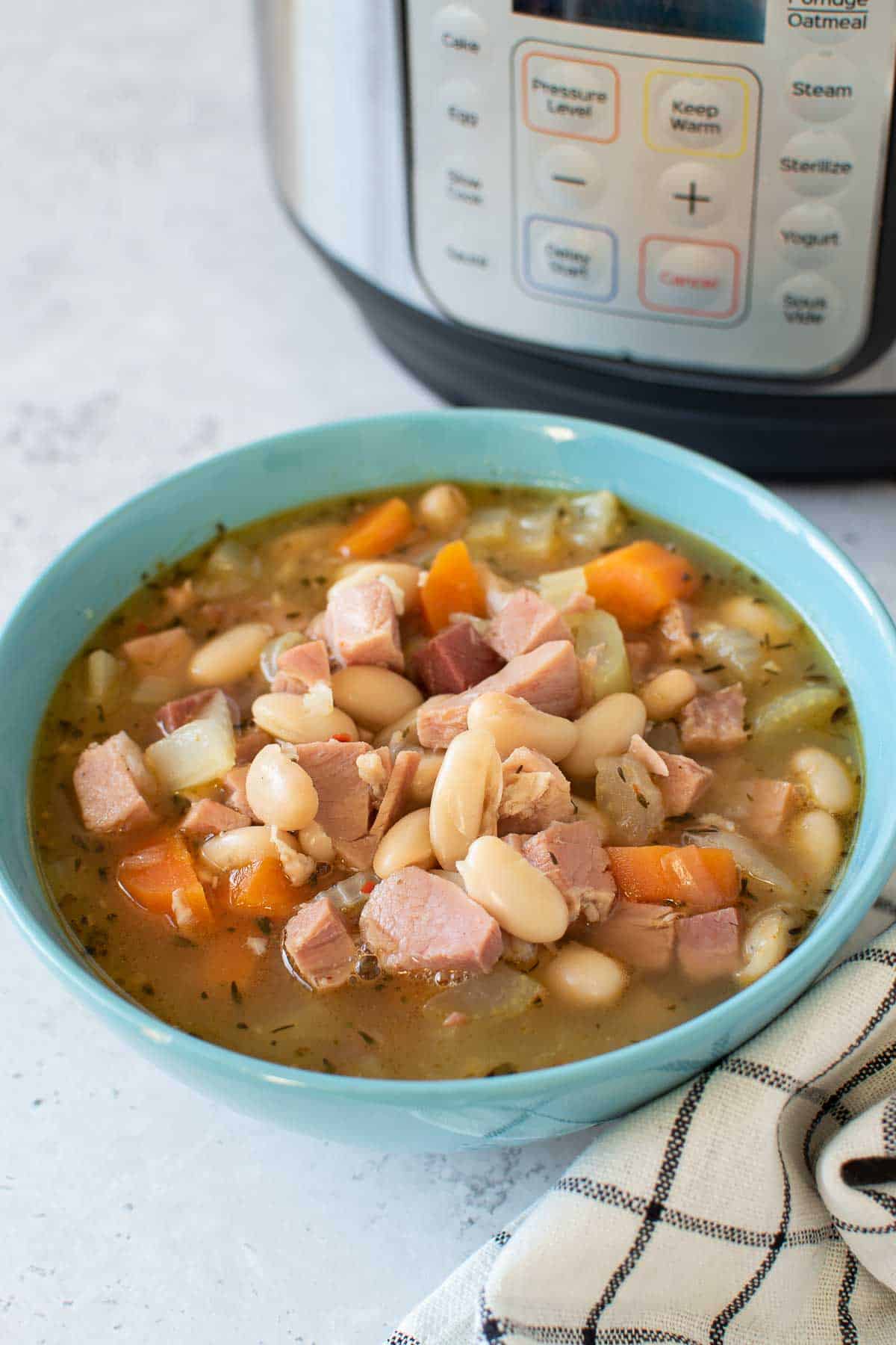 Pressure cooker ham and beans in a bowl, with an Instant Pot in the background.