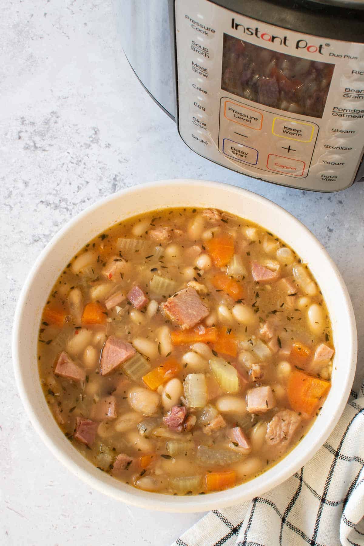 A bowl of ham and beans with carrots, onions and celery.