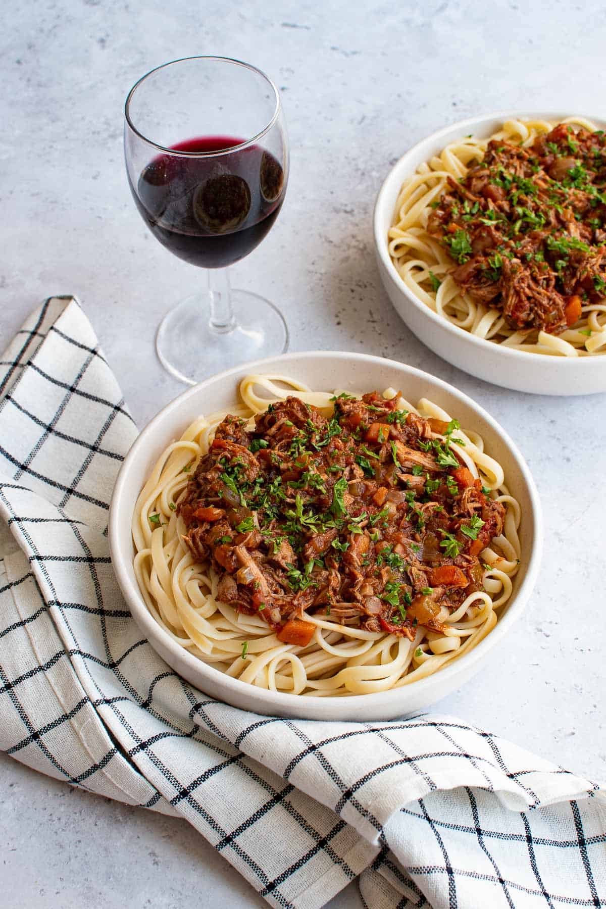 Two bowls of lamb ragu served over pasta.